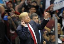 man in suit gestures with raised finger at a crowded event
