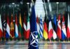 NATO flag with member country flags in the background