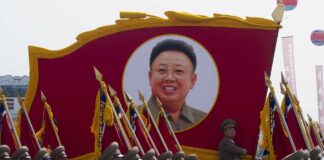 Military parade featuring soldiers and a large banner of Kim Il-sung