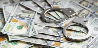 Handcuffs on scattered US hundred dollar bills