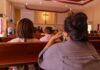 people seated in church pews facing a cross