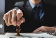 Court Smacks Down Speech-Based Visa Purge Hand stamping a document on a desk