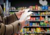 Grocery Pain Ignites Right-Wing Brawl Hands holding receipts in a grocery aisle