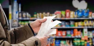 Hands holding receipts in a grocery aisle