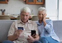 Older couple on couch looking at credit card and phone