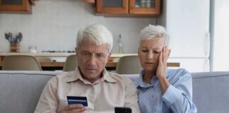 Older couple on couch looking at credit card and phone