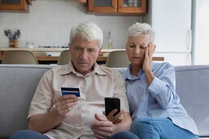Older couple on couch looking at credit card and phone
