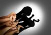 Hands forming a shadow of a fetus on a wall