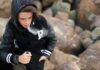 teenager in hoodie vaping among rocks