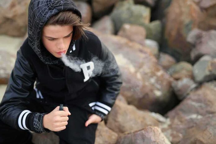 shutterstock_2251931295 teenager in hoodie vaping among rocks