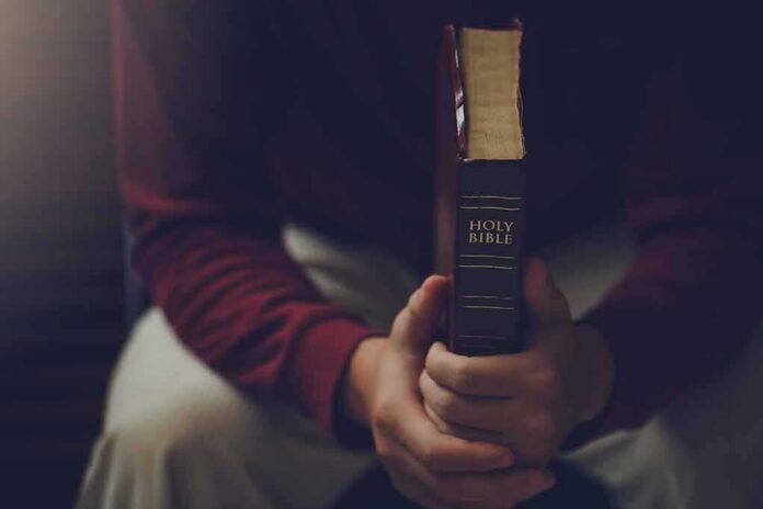 Person holding a closed Bible while seated