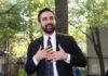 Taxpayers On Hook For Massive Hotel Deal Man in suit speaking with hands on chest outdoors