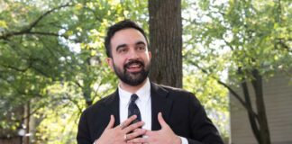 Man in suit speaking with hands on chest outdoors