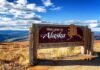 wooden welcome sign with Alaska map by open landscape