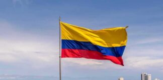 Colombian flag waving over a coastal city skyline