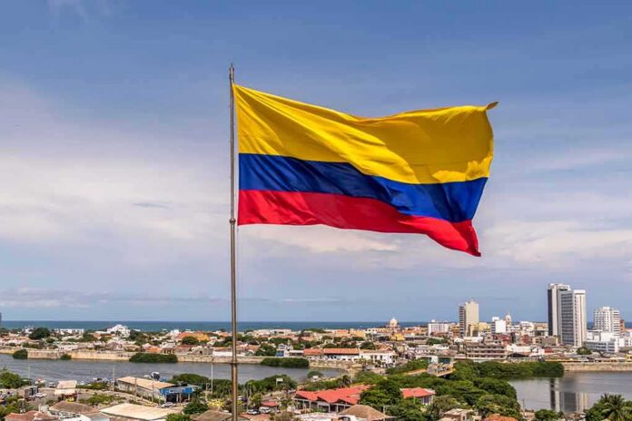 Colombian flag waving over a coastal city skyline