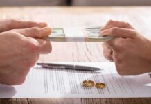 Hands tugging on a stack of cash over divorce papers