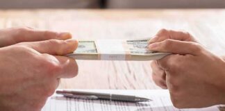 Hands tugging on a stack of cash over divorce papers