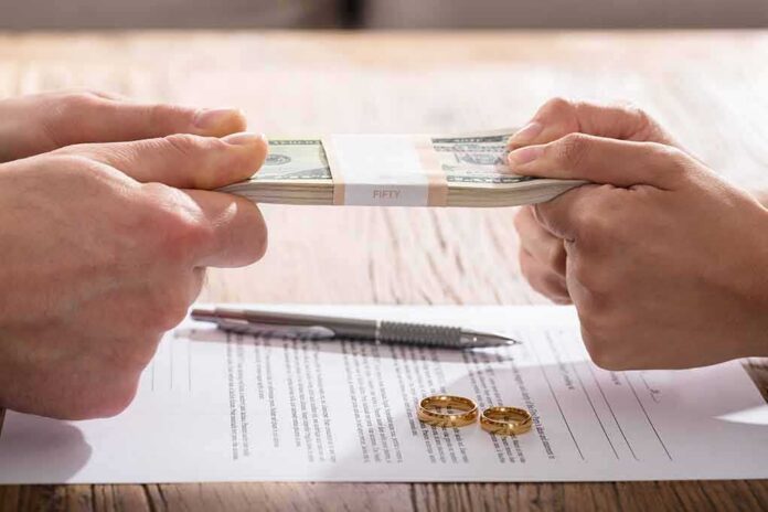 Hands tugging on a stack of cash over divorce papers