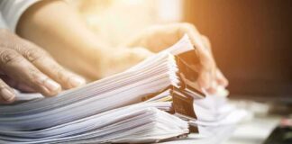 Hands sorting a large stack of paper documents with binder clips