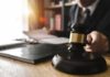 Prosecutor Undercuts ‘Armed Attack’ Hype Judge's gavel on desk with person reading documents in background