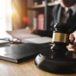 Prosecutor Undercuts ‘Armed Attack’ Hype Judge's gavel on desk with person reading documents in background