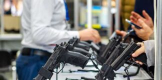 Handguns displayed on stands at a trade show counter