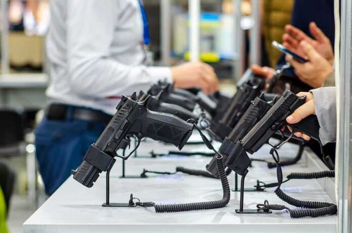shutterstock_1538947526 Handguns displayed on stands at a trade show counter