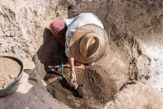 Archaeologist brushing soil in excavation pit