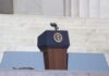 Podium with a microphone and presidential seal in front of steps