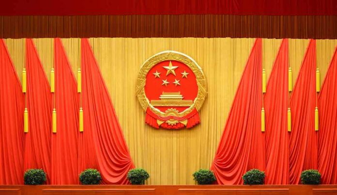 Chinese national emblem on red-draped stage backdrop