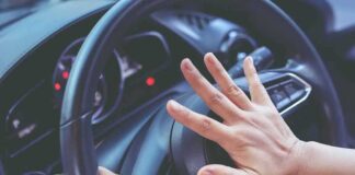 Driver pressing car horn on steering wheel