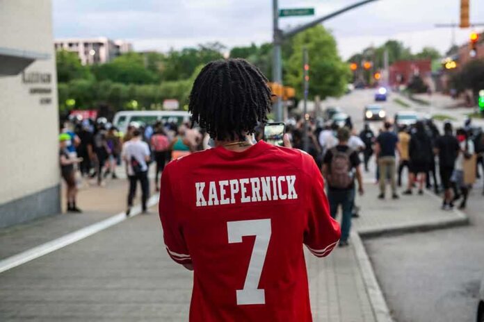 Person in red football jersey films a street protest