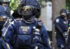 Federal Knock At Door Over ‘Harsh’ Email Riot police officer in tactical gear with helmet and visor