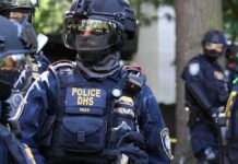 Federal Knock At Door Over ‘Harsh’ Email Riot police officer in tactical gear with helmet and visor