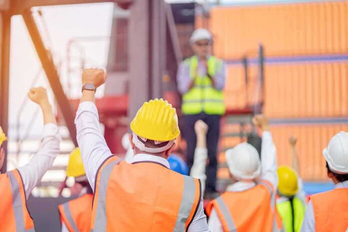 shutterstock_1919760773 construction workers raising fists during a safety briefing