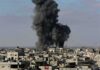 Hospital Blackouts Spark Deadly Gamble Thick black smoke rises from an explosion over a dense urban area