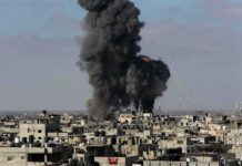 Hospital Blackouts Spark Deadly Gamble Thick black smoke rises from an explosion over a dense urban area