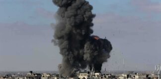 Thick black smoke rises from an explosion over a dense urban area