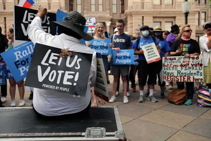 shutterstock_1995915851 Christian Jones sits with a 'Let Us Vote' sign facing a crowd at a voting rights rally
