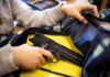 hand reaches into backpack with a handgun inside
