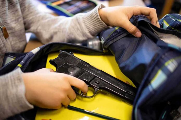 shutterstock_2074388671 hand reaches into backpack with a handgun inside