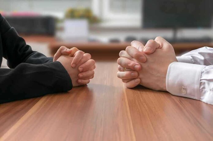 shutterstock_371954932 Clasped hands of two people at a table