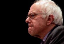 Superintelligence Ban? Sanders Lights the Fuse Bernie Sanders in profile wearing glasses against a black background