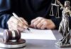 Psychosis Or Plot? Illinois Case Stuns Judge writing at desk with gavel and Lady Justice statue