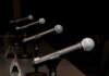 Row of microphones on stands at a panel table
