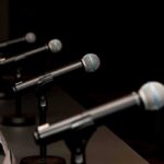 Row of microphones on stands at a panel table