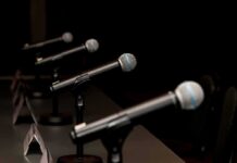War Profits Claim Torches Maine Showdown Row of microphones on stands at a panel table