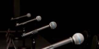 Row of microphones on stands at a panel table