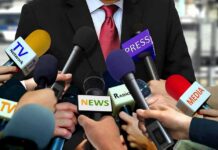 Label Trap : Trump Pick Tiptoes Press microphones surround a suited spokesperson